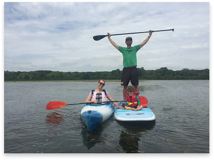 Woman on a kayak and a man on a paddleboard with boy